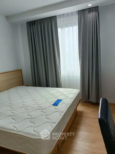 Cozy bedroom with natural light, featuring a comfortable bed and stylish curtains, perfect for relaxation.