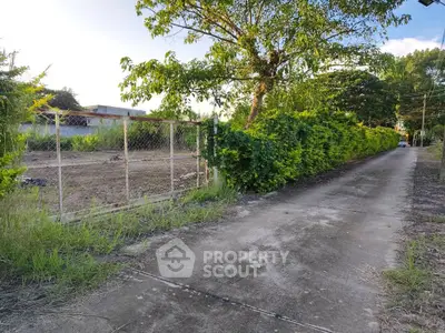 Spacious plot of land with lush greenery and a paved pathway, ideal for development opportunities.