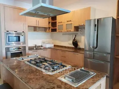 Modern kitchen with marble countertop, gas stove, and stainless steel appliances.