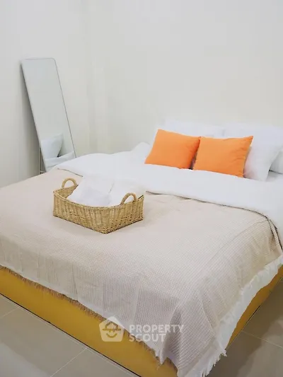 Cozy bedroom with modern decor and vibrant orange pillows