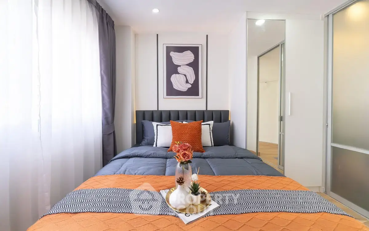 Modern bedroom with stylish decor and natural light, featuring a cozy bed and elegant artwork.