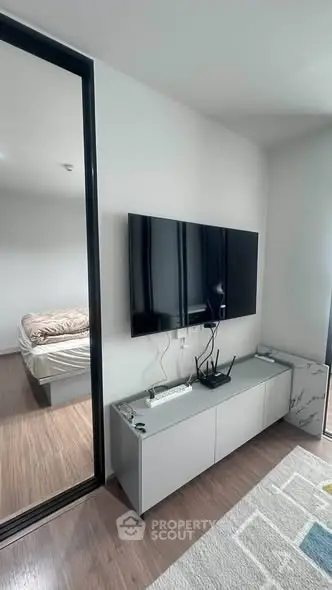 Modern living room with sleek TV setup and view into cozy bedroom