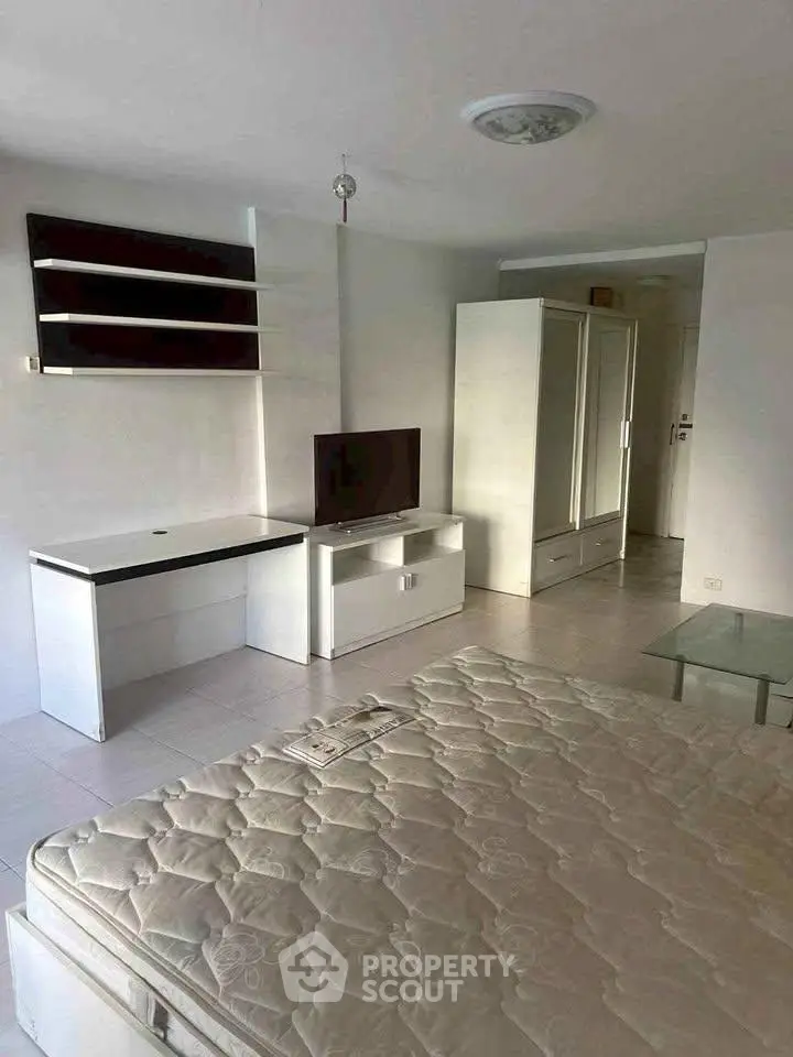 Spacious bedroom with modern furniture and ample storage in a well-lit apartment.