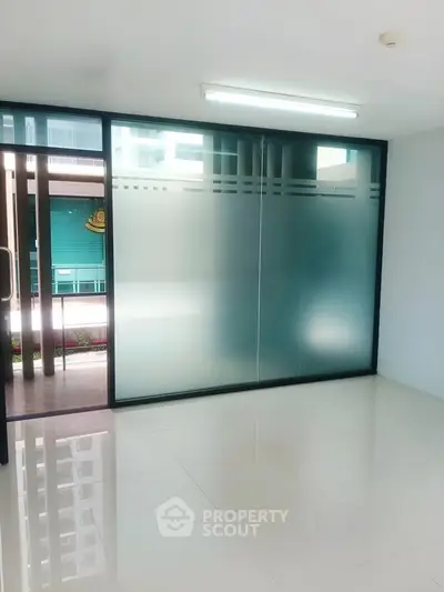 Modern office space with frosted glass doors and sleek tile flooring.