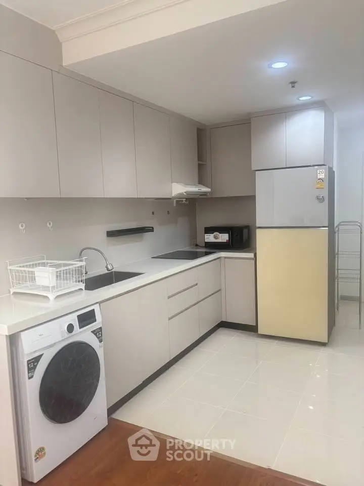 Modern kitchen with sleek cabinetry, washing machine, and fridge in a stylish apartment.