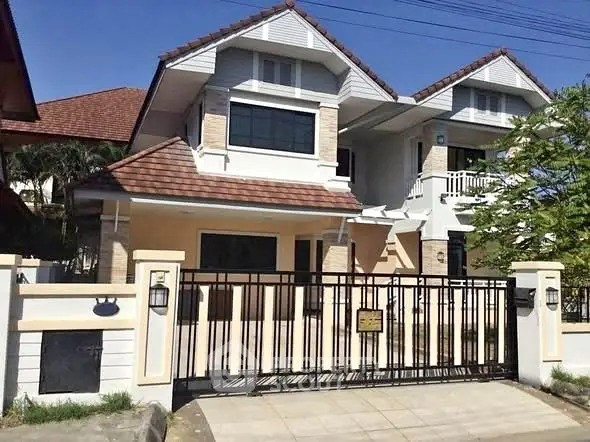 Charming two-story house with gated entrance and tiled roof in sunny neighborhood.