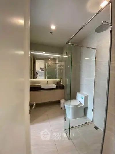 Modern bathroom with glass shower and sleek fixtures in contemporary apartment.