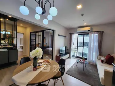 Modern living room with stylish decor and open layout, featuring a dining area and large windows for natural light.