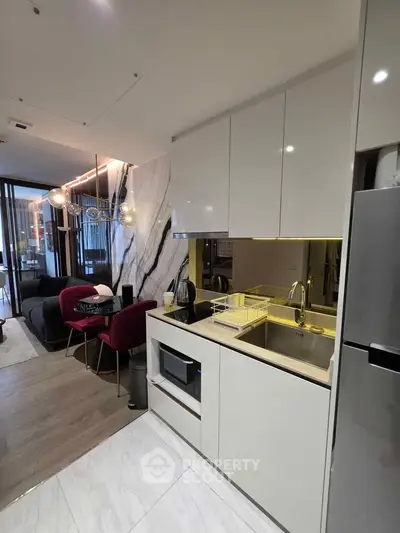 Modern open-layout kitchen with sleek cabinetry and stylish living area in luxury apartment.