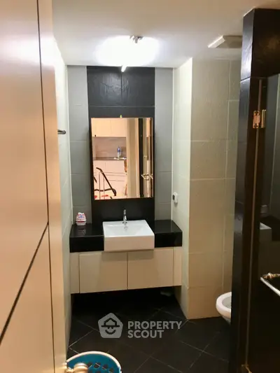 Modern bathroom with sleek sink and mirror, featuring contemporary black and white tile design.