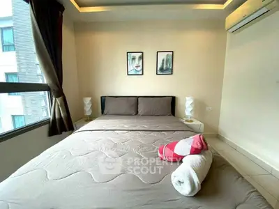 Cozy bedroom with modern decor and large window offering natural light.