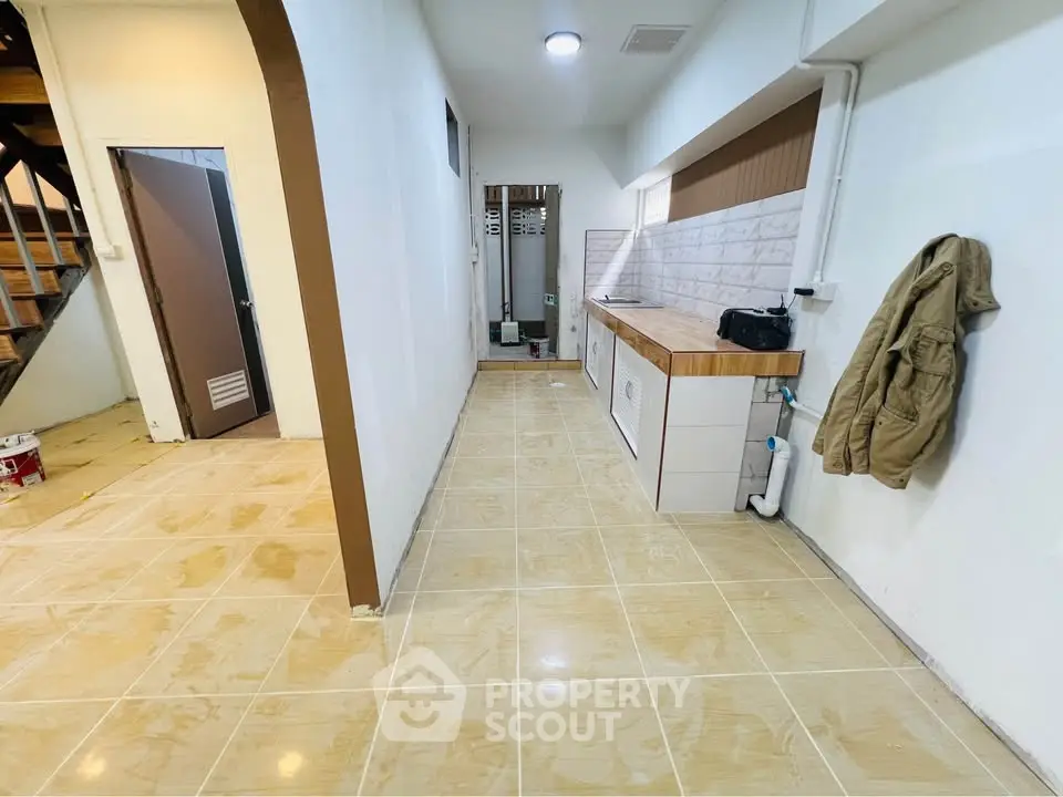 Spacious hallway with tiled flooring and modern cabinetry, ideal for storage or utility use.