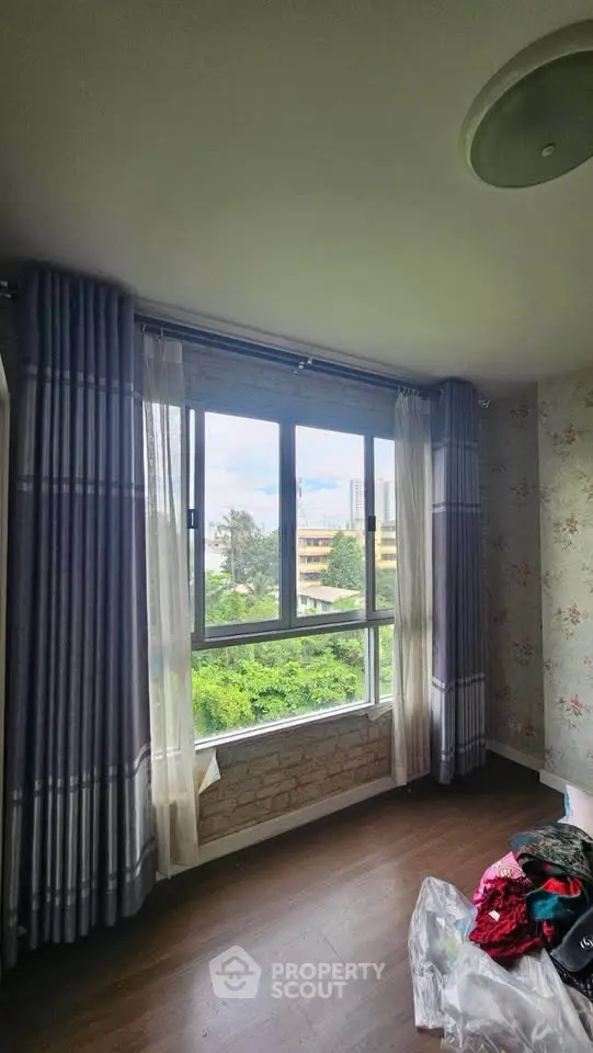 Bright room with large window offering lush green view, ideal for serene living.