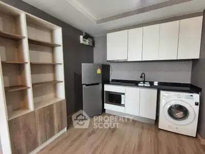 Modern kitchen with sleek cabinets, washing machine, and fridge in a compact layout.