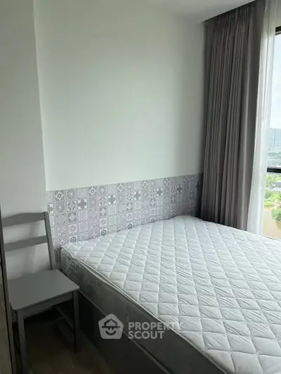 Cozy bedroom with large window and modern decor in a high-rise apartment.