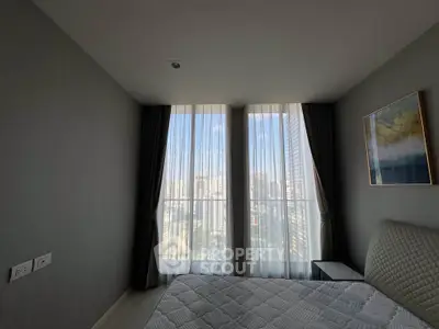 Modern bedroom with city view, featuring large windows and elegant decor.