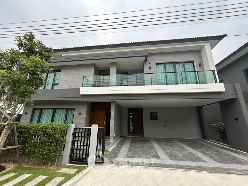 Modern two-story house with spacious driveway and sleek balcony design.
