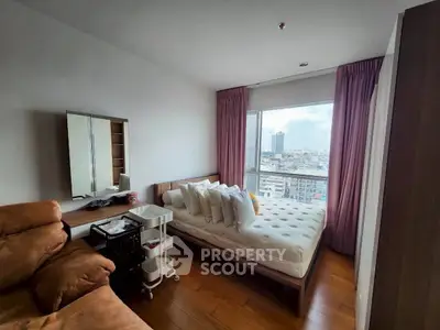 Cozy bedroom with city view, featuring a comfortable bed, plush seating, and ample natural light.