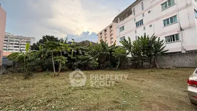 Spacious garden area with lush greenery beside residential buildings, perfect for outdoor activities.