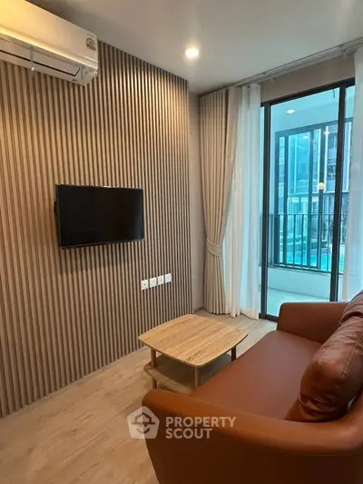 Modern living room with sleek design and pool view, featuring a cozy sofa and wall-mounted TV.