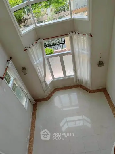Spacious living room with high ceilings and large windows offering abundant natural light.