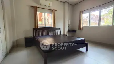 Spacious bedroom with large windows and modern furnishings in a serene residential area.