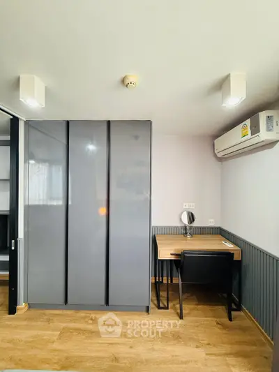 Modern study room with sleek desk and built-in wardrobe, featuring wood flooring and air conditioning.