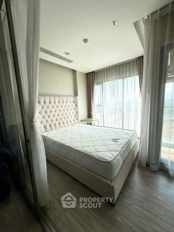 Spacious bedroom with elegant decor and large windows offering natural light