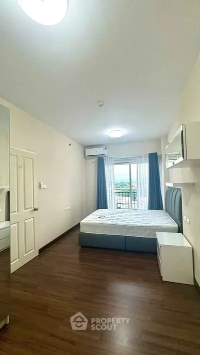 Spacious bedroom with modern furnishings and balcony view in a stylish apartment.