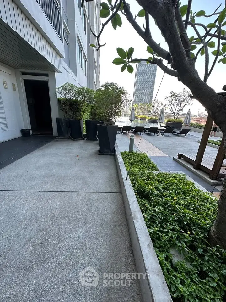 Modern building exterior with lush greenery and outdoor seating area.