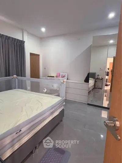 Modern bedroom with sleek flooring and mirrored wardrobe, perfect for a cozy living space.