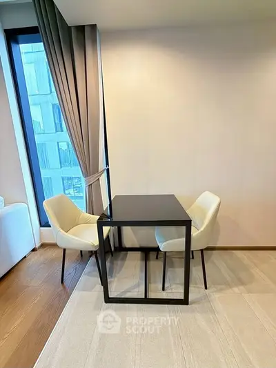 Modern minimalist interior with sleek black table and elegant chairs by a large window.