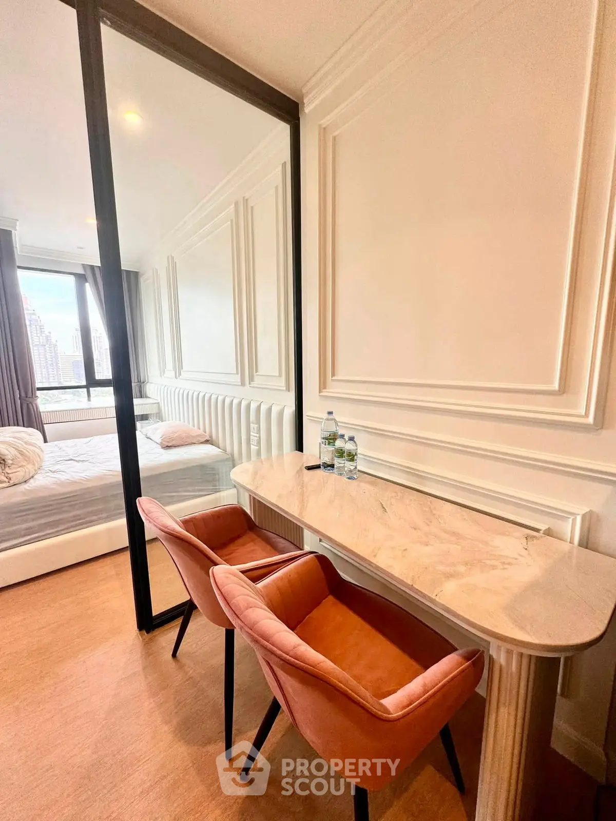 Elegant bedroom with stylish desk and chairs, featuring a luxurious bed and large window with city view.