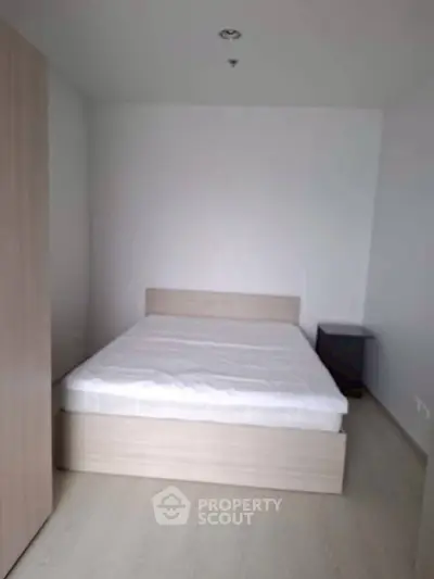 Minimalist bedroom with wooden bed frame and side table, perfect for modern living.