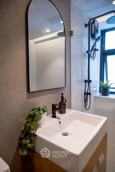 Modern bathroom with stylish sink and shower, featuring elegant fixtures and natural light.