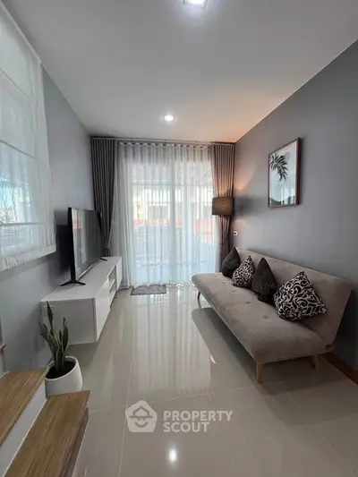 Modern living room with sleek design, featuring a comfortable sofa, large TV, and elegant curtains.