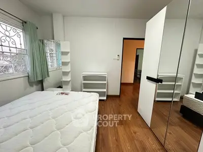 Spacious bedroom with wooden flooring and mirrored wardrobe in modern apartment.