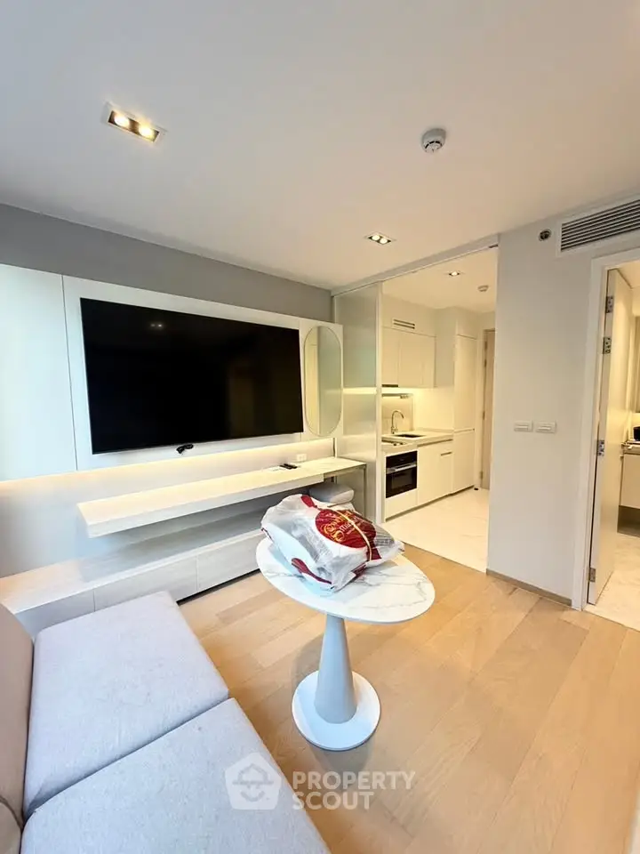 Modern living room with sleek TV setup and open kitchen layout in a stylish apartment.