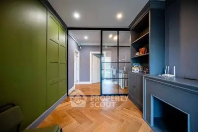 Modern living room with stylish green accent wall and sleek wooden flooring.