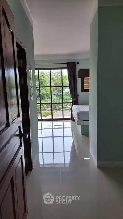 Spacious bedroom with large windows offering a serene garden view, perfect for relaxation.