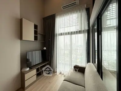 Modern living room with large window and city view, featuring sleek furniture and neutral tones.