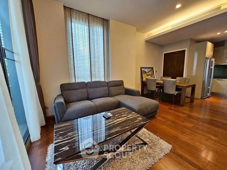 Modern living room with stylish furniture and open kitchen layout, featuring hardwood floors and elegant decor.