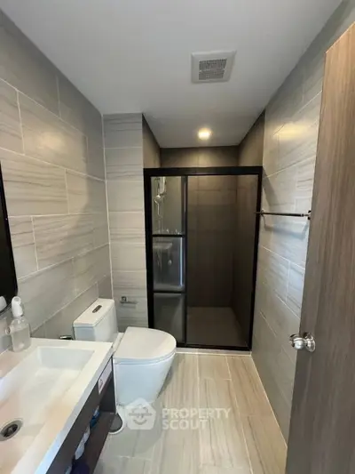 Modern bathroom with sleek shower and contemporary fixtures in stylish real estate property.