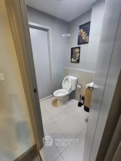 Modern bathroom with sleek design and elegant wall art, featuring a contemporary toilet and neutral color palette.