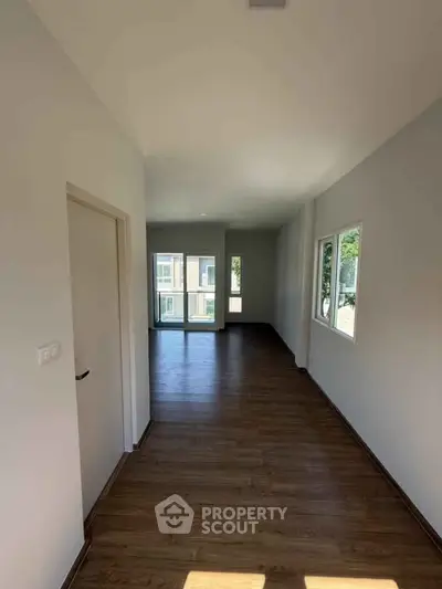 Spacious empty room with large windows and wooden flooring, ideal for customization.