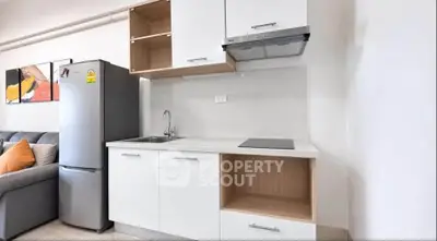 Modern compact kitchen with sleek cabinets and stainless steel appliances in a cozy apartment.
