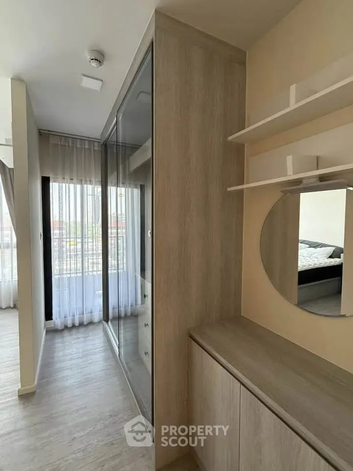 Modern bedroom with stylish wardrobe and mirror, featuring floor-to-ceiling windows for natural light.