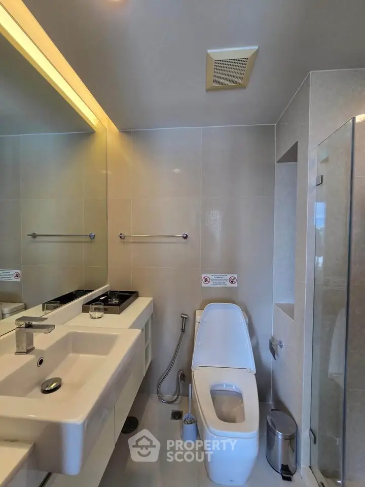 Modern bathroom with sleek fixtures and spacious layout, featuring a large mirror and contemporary design.
