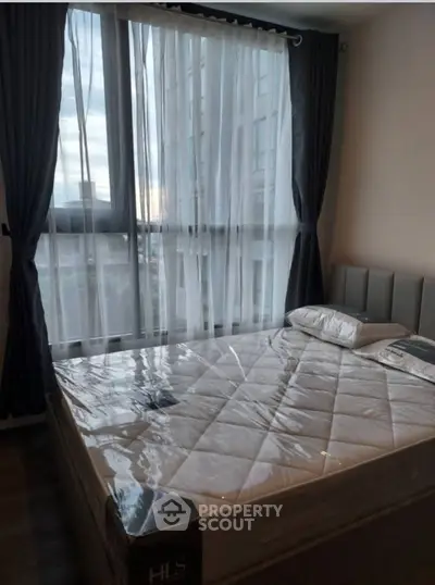 Cozy bedroom with large window and modern bed in a high-rise apartment.