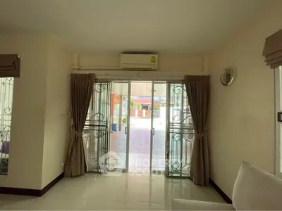 Spacious living room with sliding glass doors leading to a patio, featuring elegant curtains and air conditioning.